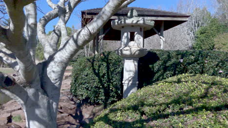 Tilt-shot-to-Japanese-lantern,-in-gardens-of-Ju-Raku-En-Japanese-Garden,-Toowoomba-Australia