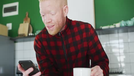 thoughtful albino african american man with dreadlocks using smartphone