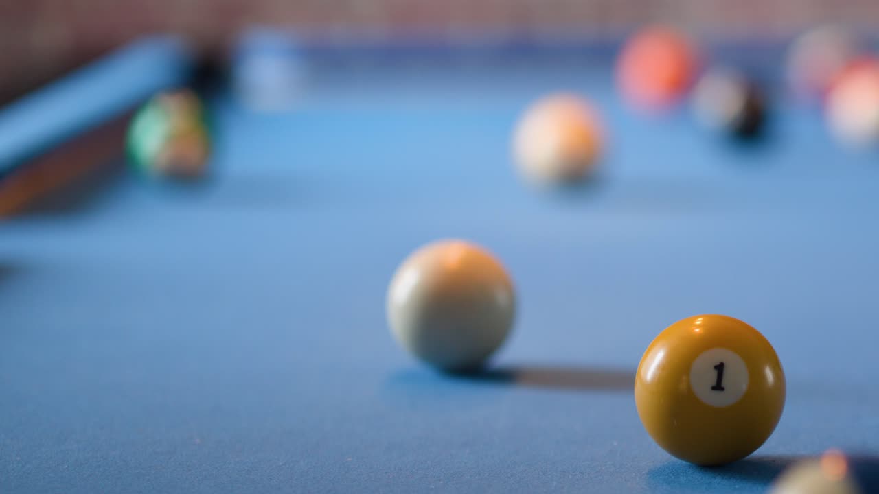 Yellow one ball and cue ball on blue felt pool table, shallow depth of field