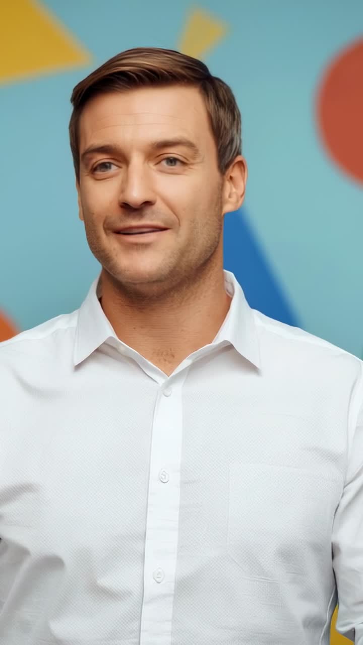 Vertical video: Smiling host in white shirt speaking, gesturing for clarity on teal set with shapes