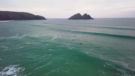 Two-surfers-make-their-way-out-to-sea-over-in-coming-waves