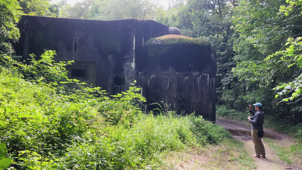Abandoned fort surrounded by lush greenery with a person walking on a path near the structure
