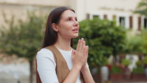 young european woman praying with closed eyes to god asking for blessing help forgiveness outdoors