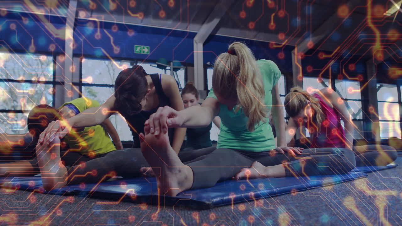 Five women doing forward bend stretch in gym studio showing digital circuit overlay for health tech
