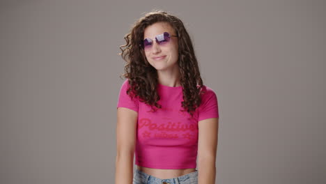 brunette girl puts on heart-shaped sunglasses and poses, studio shot