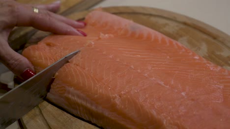 mujer cortando filete de salmón con un cuchillo de cocina