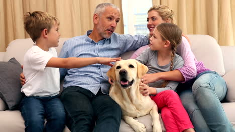 familia feliz acariciando a un labrador en el sofá