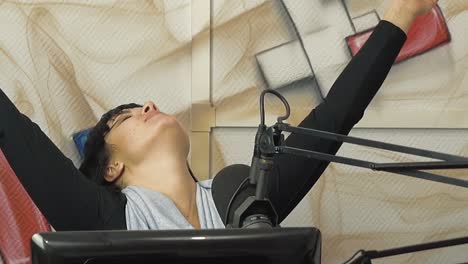 radio dj in the broadcast studio the girl puts a finger to her head representing fatigue