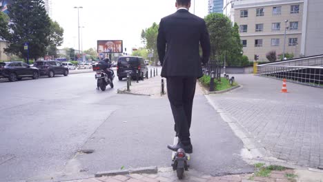 Hombre-Con-Traje-Formal-Montando-Scooter-Eléctrico-En-La-Ciudad.