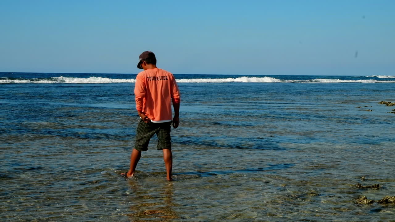 hombre caminando en el agua en bacnotan la union beach, isla immuki, filipinas