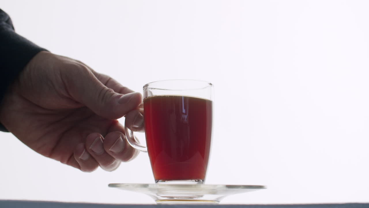 짙은 차와 커피가 담긴 컵을 손으로 잡고 컵을 접시에 다시 놓습니다.