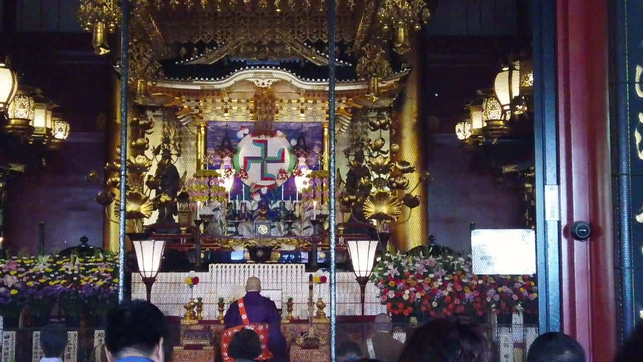 gente y un sacerdote budista rezando frente al altar dentro del templo budista en japón