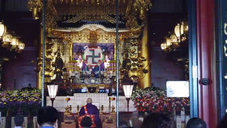 日本の仏教寺院内の祭壇の前で祈る人々と僧侶