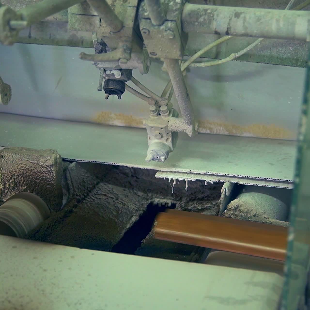 Conveyor belt with wooden plank moving along. Equipment spraying varnish on wooden door billet