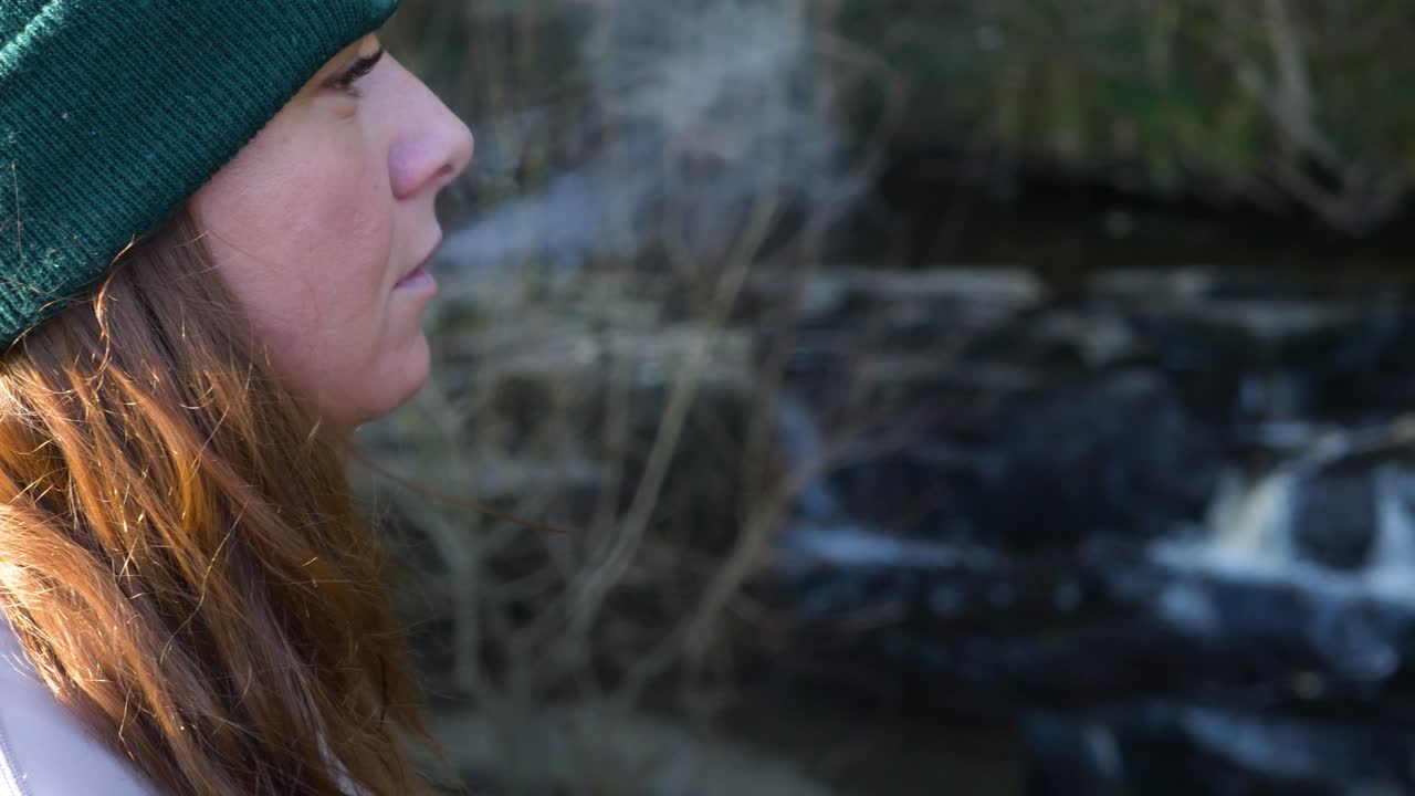 Una donna che svapa nella foresta di Cathole Falls, nella contea di Laois, Irlanda. Primo piano.
