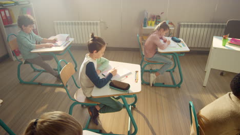 students doing class work. schoolboys and schoolgirls writing in notebooks