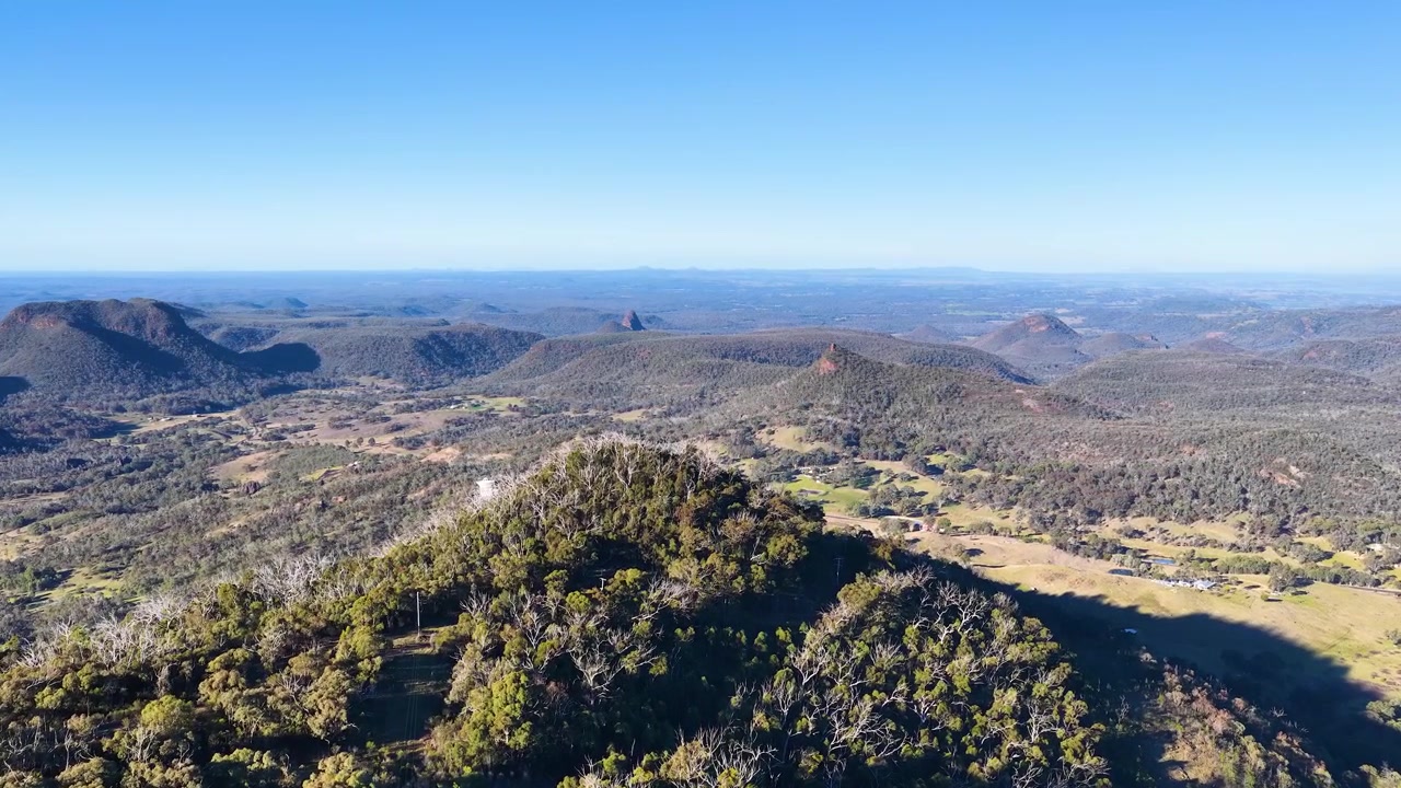 Tomada panorâmica ampla de cadeias de montanhas vulcânicas sob céu azul claro no Parque Nacional Warrumbungle.