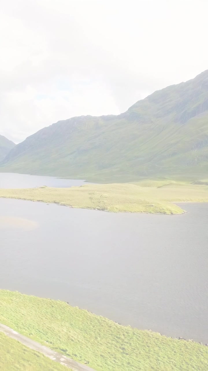 縦型動画：窓ガラスに反射する赤い光の筋、右下へパンしながら湖の島を映し出す映像の軌跡