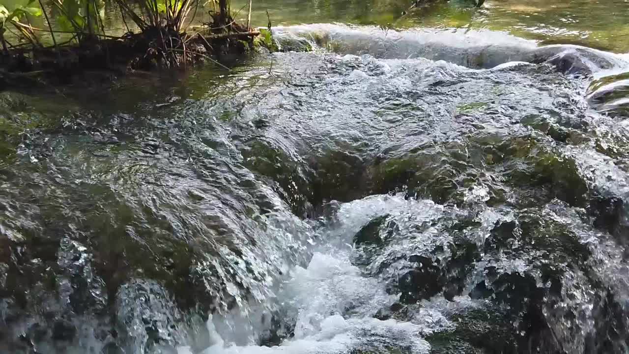 Inquadratura inclinata dell'acqua che scorre a cascata lungo una superficie rocciosa in una pozza di bolle nel Parco Nazionale dei Laghi di Plitvice in Croazia, Europa a ¼ di velocità