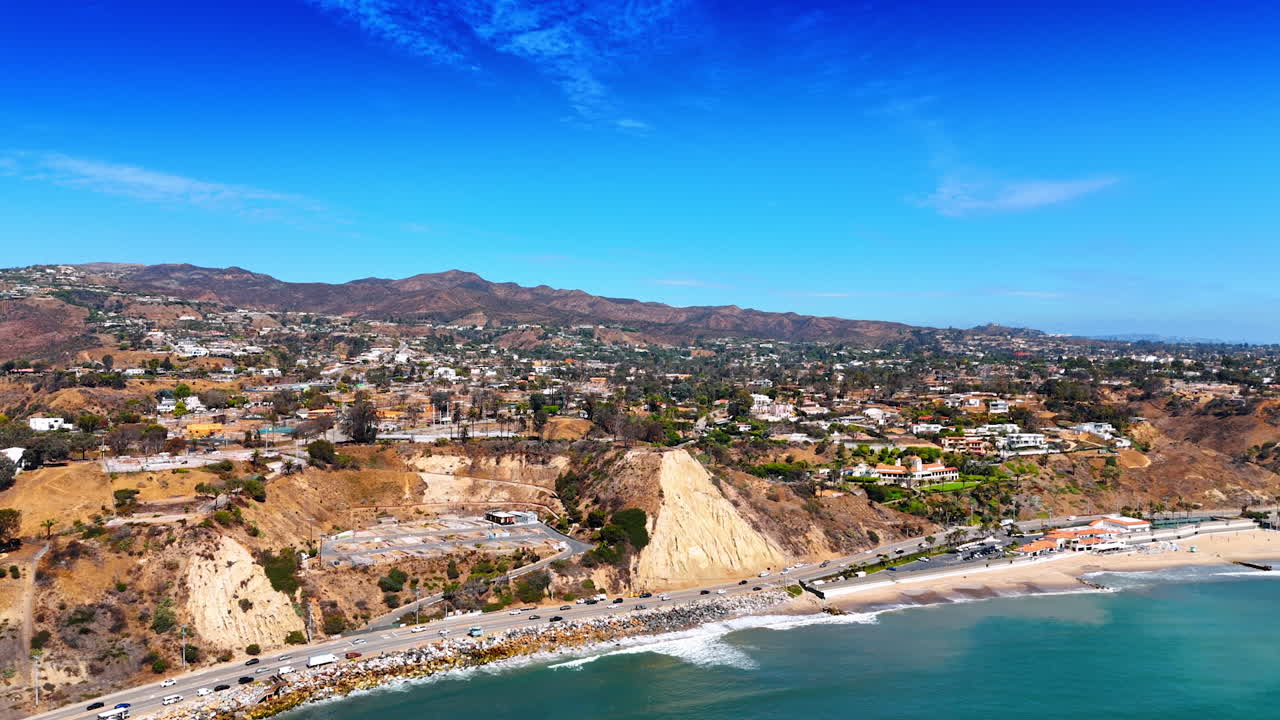 Rocky landscape of sunny Malibu, California, USA. Drone footage over the blue waterscape with the view on the road along the shore