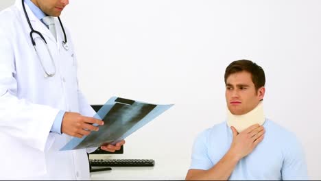 doctor showing xray to injured patient in neck brace