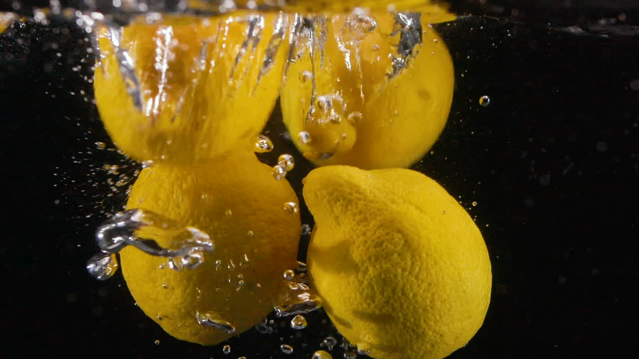 Bunch of Slow Motion Citrus Lemons Drop in Water Cool Bubbles