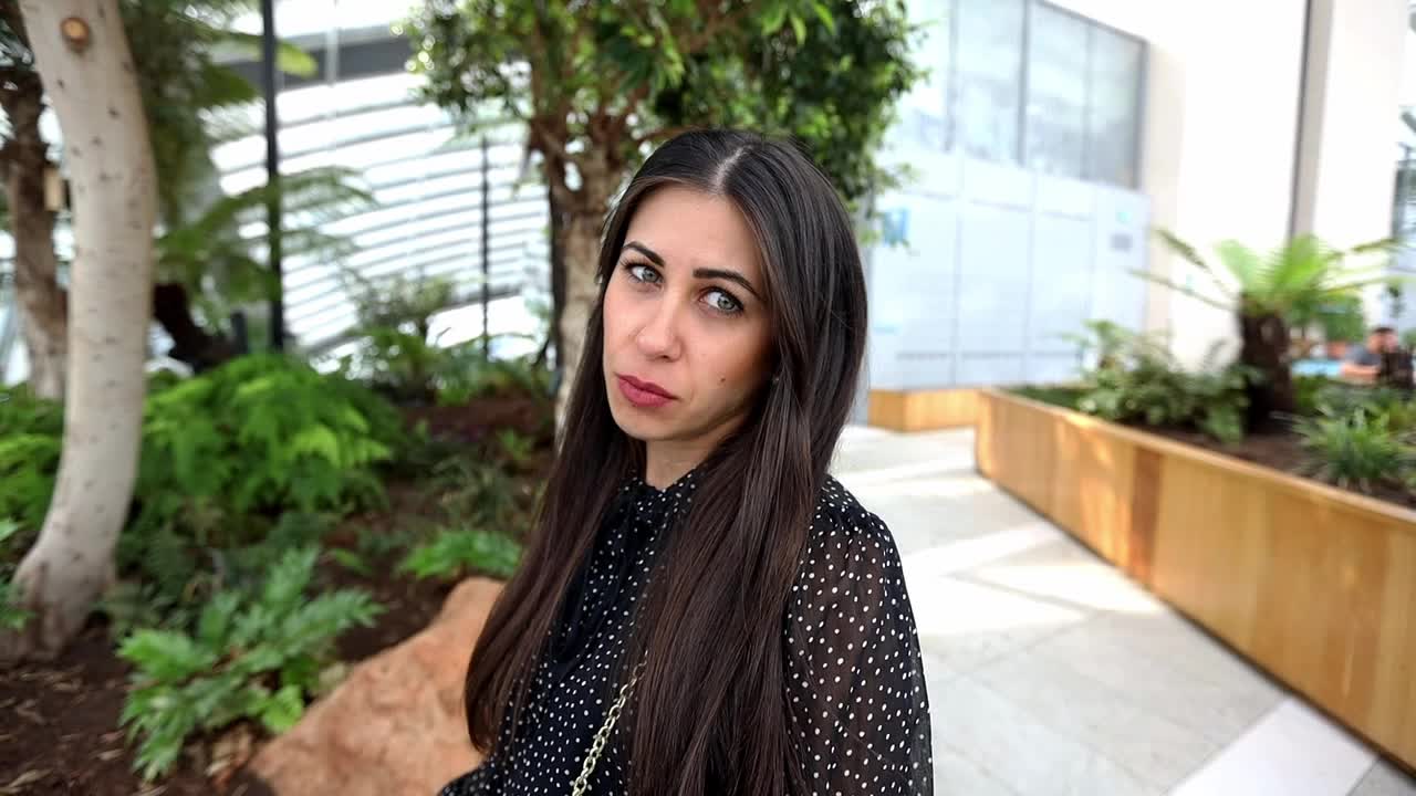 una hermosa chica de cabello oscuro mirando a la cámara con una cara de pensamiento triste en un entorno urbano