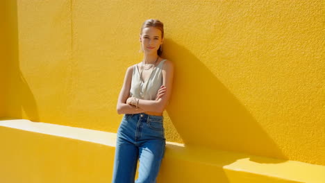 woman in casual clothes posing against a yellow wall