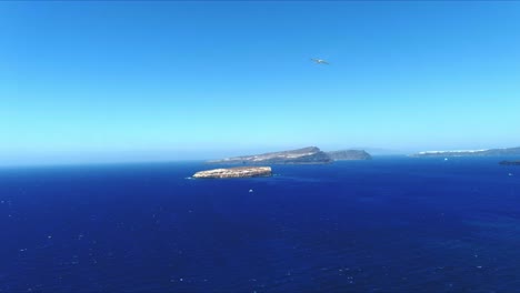 aerial 4k blue sea and sky top view towards distant tropical islands and oia in santorini greece