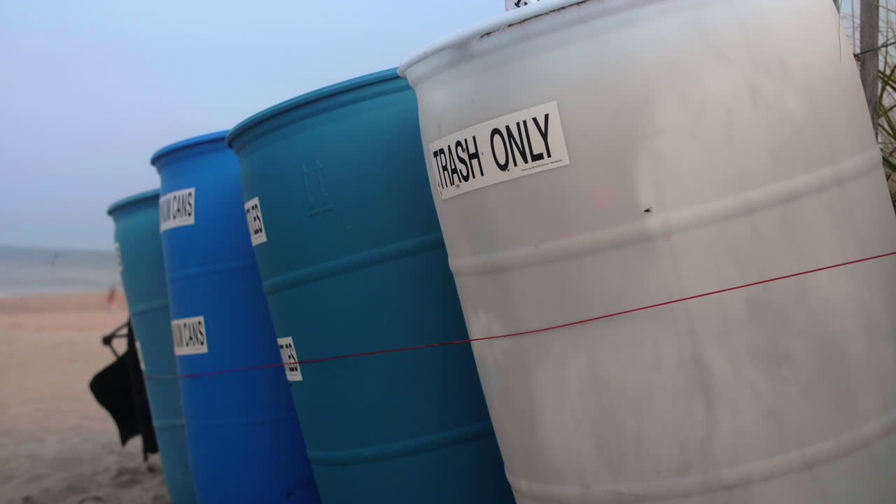 contenedores de basura y reciclaje con moscas en la playa, inclinación hacia arriba, cámara lenta