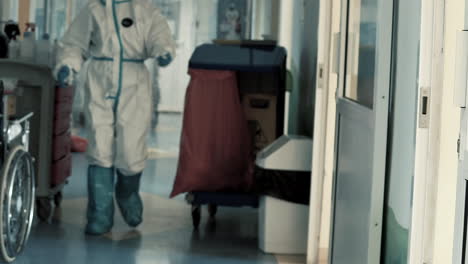 hospital worker janitor in full covid-19 protective gown equipment cleaning hallway