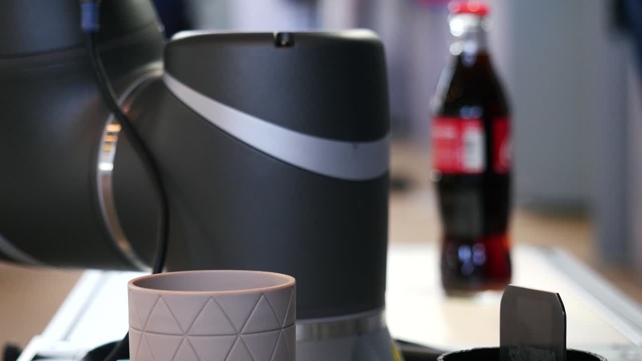 Robot industriale e bottiglia di bibita a una mostra