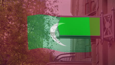 waving green and white crescent flag over urban street with autumn trees