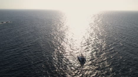 Vista-Aérea-De-La-Navegación-En-Catamarán-En-El-Mar-Egeo-Por-La-Isla-De-Santorini,-Grecia-En-La-Luz-Del-Sol-De-La-Hora-Dorada