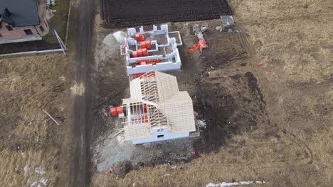 aerial view of unfinished frame of private house with aerated lightweight concrete walls and wooden roof frame under construction