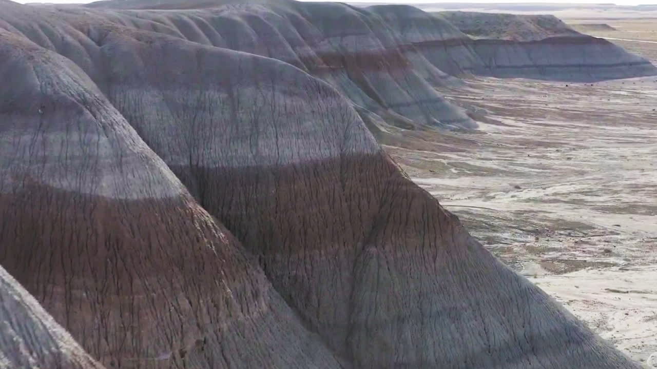 A fast pace drone footage of the brown and red rocky hills in Badlands, revealing furhter land of the stunning landscape. Arizona, USA