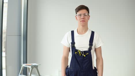 young master in work uniform and protective glasses looking at the camera