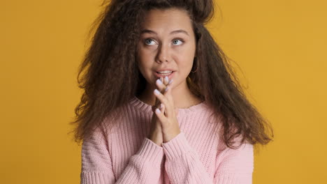 caucasian curly haired woman making a wish to the camera.