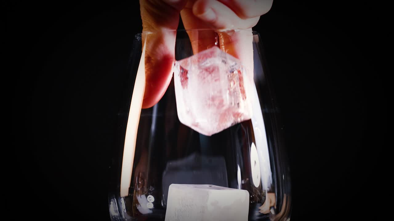 손은 빈 유리잔에 얼음 큐브를 떨어뜨립니다.