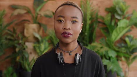retrato de una joven mujer afroamericana de aspecto serio, atractiva y negra, estudiante de sexo femenino con un fondo de plantas de moda elegante