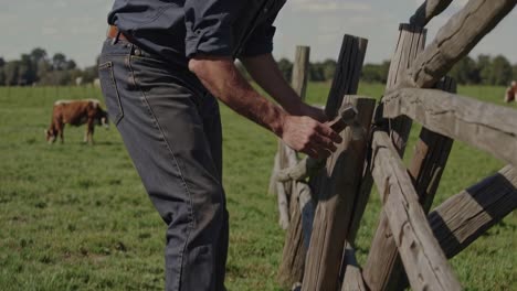 farmer repairing a wooden fence