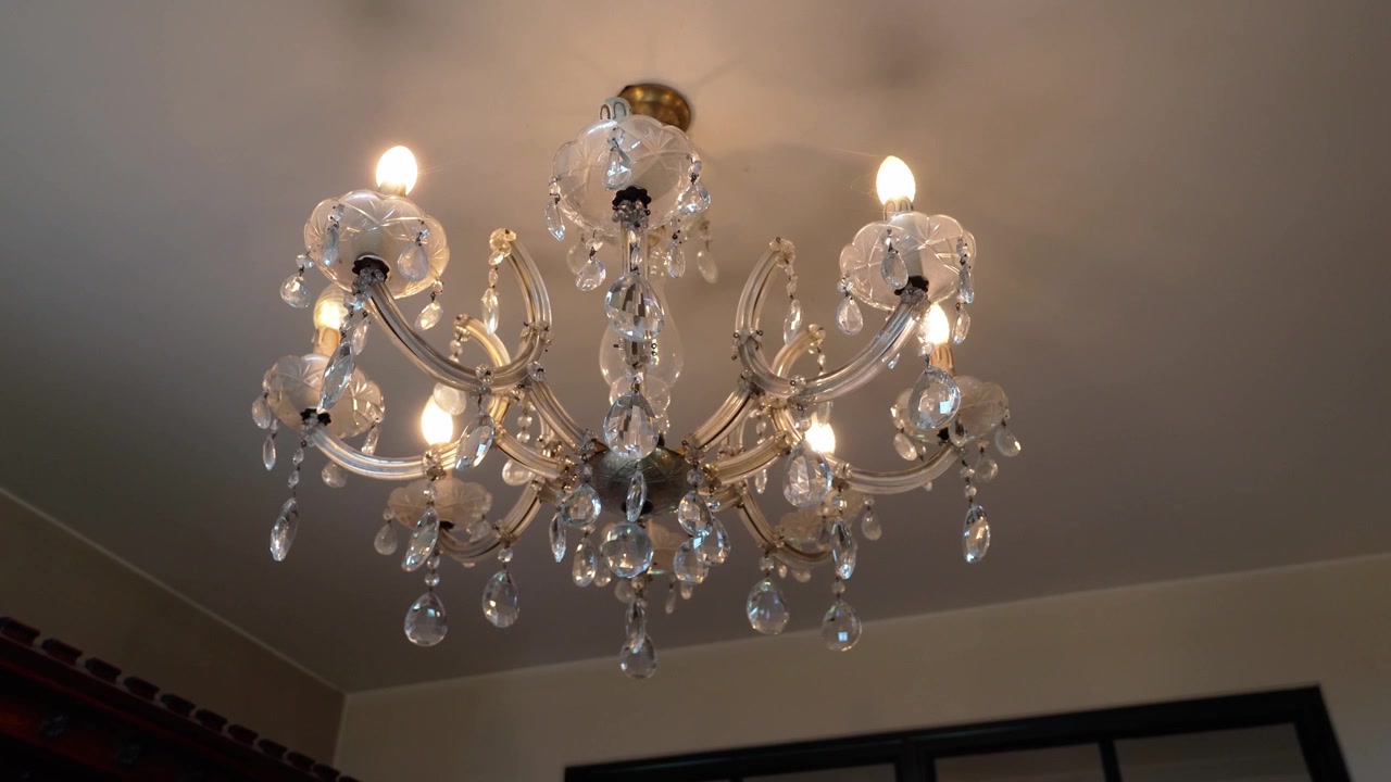 Ripresa panoramica con rotazione dal basso di una bellissima lanterna appesa al soffitto che emana una luce calda.
