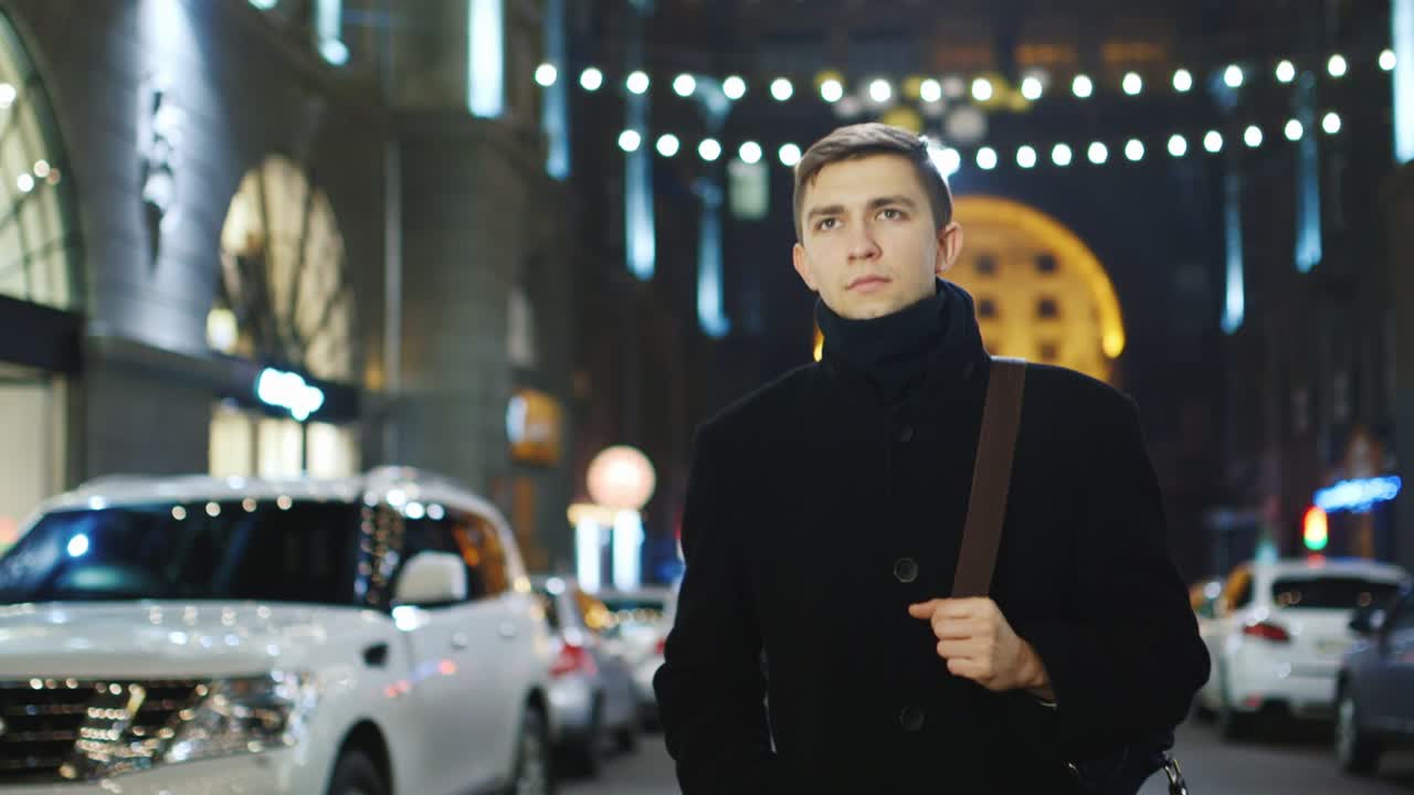 un joven camina por la ciudad nocturna y usa un teléfono inteligente 3