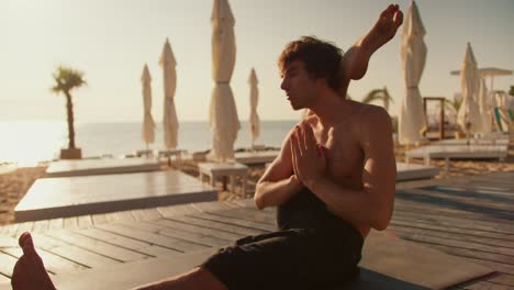 el yogui mantiene el pie detrás de la cabeza y medita en una playa soleada por la mañana. estilo zen, armonía de cuerpo y mente