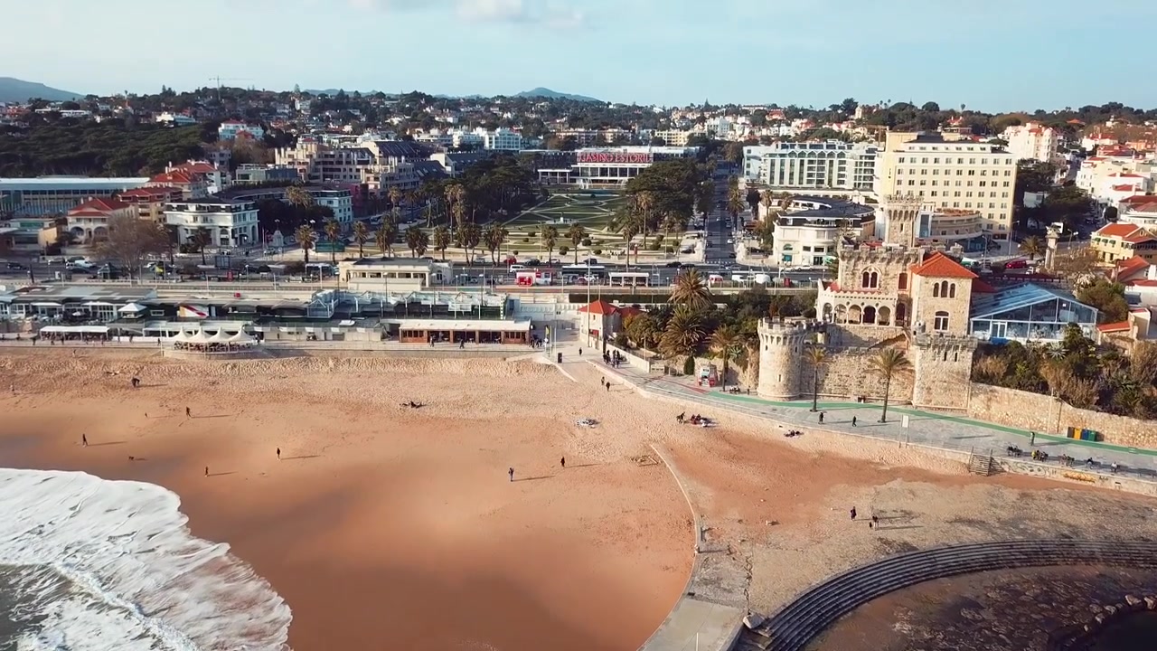 Dron sobre la playa de Estoril en Lisboa, Portugal. El casino y el fuerte son visibles con coches pasando por la calle principal