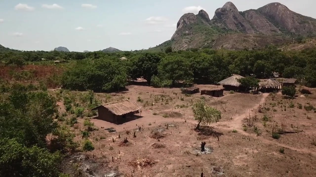 Sorvolo circolare sopra una capanna remota nel Mozambico settentrionale rurale, circondata da savana e montagne
