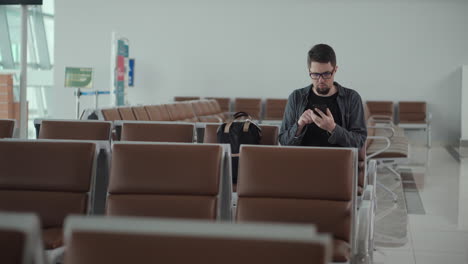 hombre usando teléfono inteligente en la zona de espera del aeropuerto