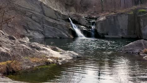 slow backward drone flight over water in near of a waterfall at daytime