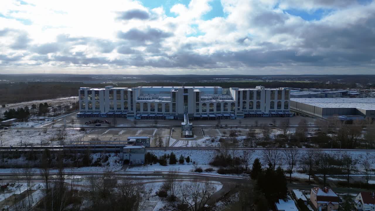 Large distribution center with loading docks and parking lot under a cloudy sky in winter. Unbelievable aerial view flight panorama overview drone