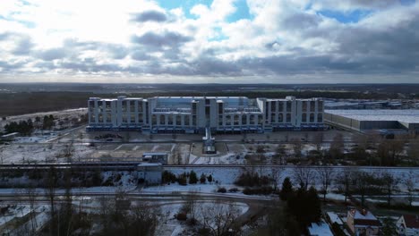 large distribution center with loading docks and parking lot under a cloudy sky in winter. unbelievable aerial view flight panorama overview drone